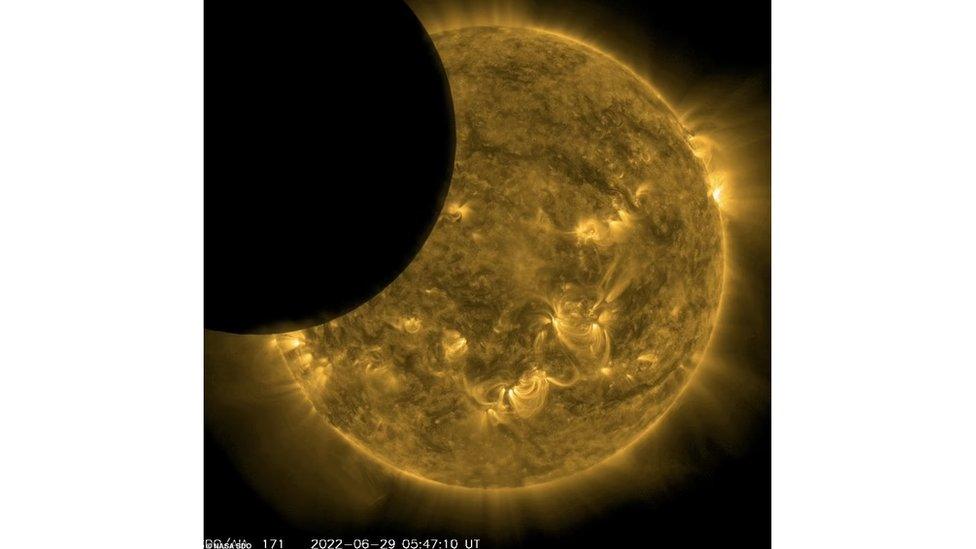 A black disc appears to the left of a still of the sun, partially covering the view