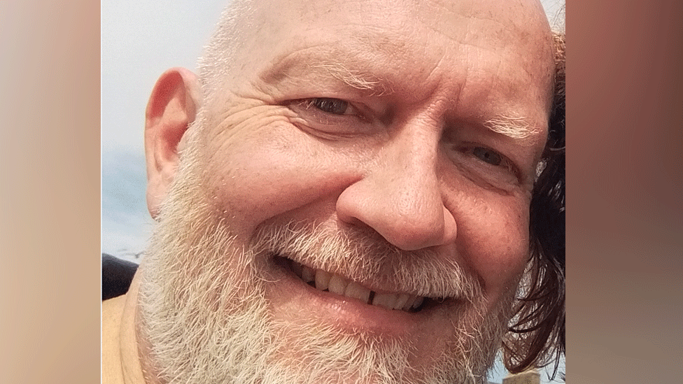 Balding middle-aged white man with cropped white hair and beard