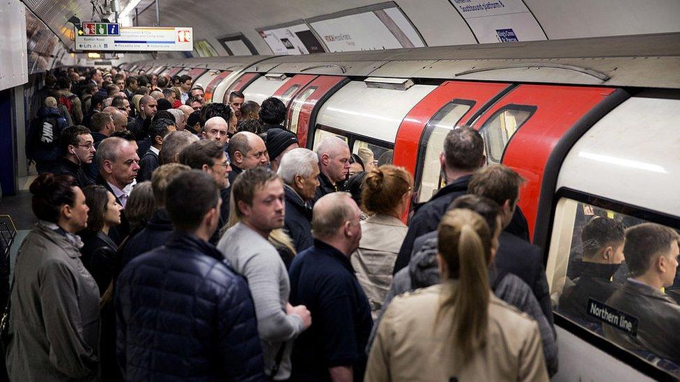 A crowded tube platform as commuters wait to board