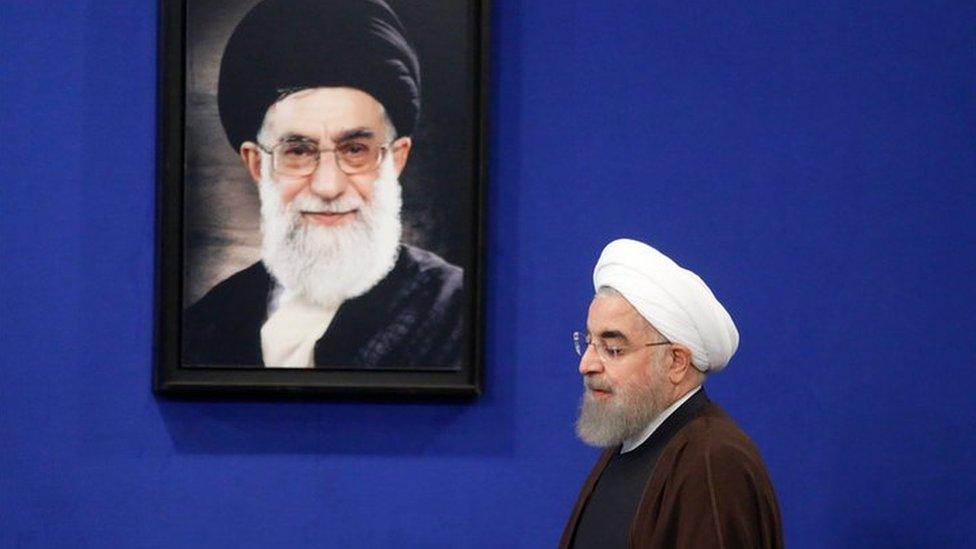 Newly re-elected Iranian President Hassan Rouhani walks past a picture of Iranian Supreme leader Ayatollah Ali Khamenei