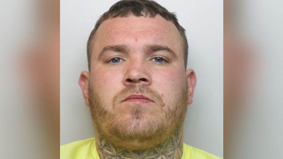 A mugshot of a man in a yellow t shirt.