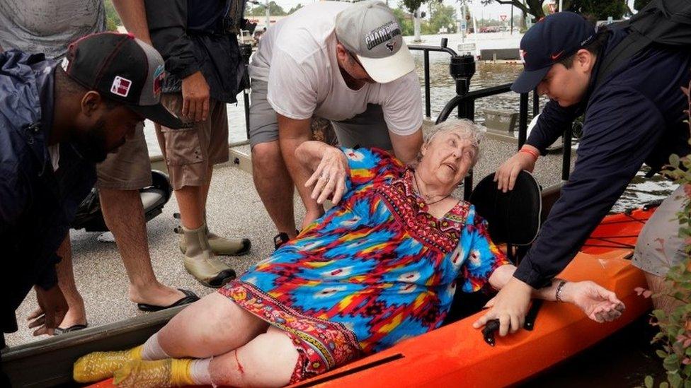 A resident is moved from a rescue boat on to a kayak in Dickenson, Texas (27 August 2017)