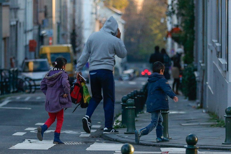 A father and his two children walking down the street after discovering the doors to their school closed in Brussels, Belgium, 23 November 2015