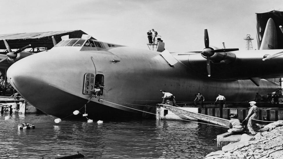 American aviator Howard Hughes (in hat) atop his flying boat the Spruce Goose (a Hughes H-4 Hercules), directing operations for the launch at Long Beach, 6th November 1947.