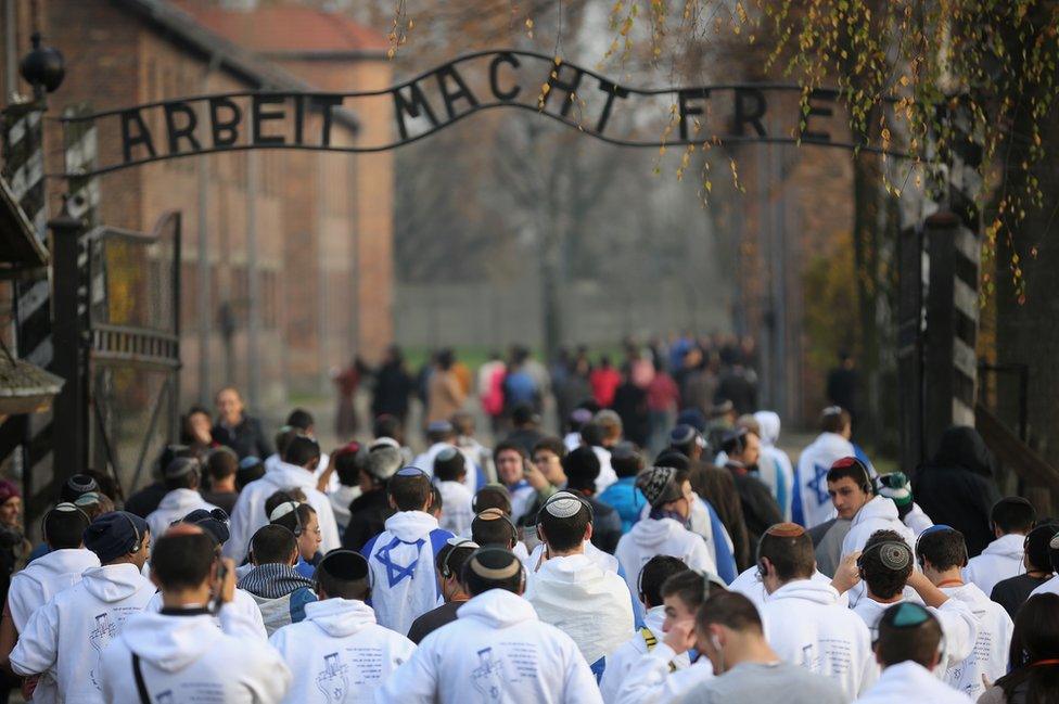 Young Israelis walk under the infamous German inscription that reads 'Work Makes Free' at the main gate of the Auschwitz I extermination camp in November 2014