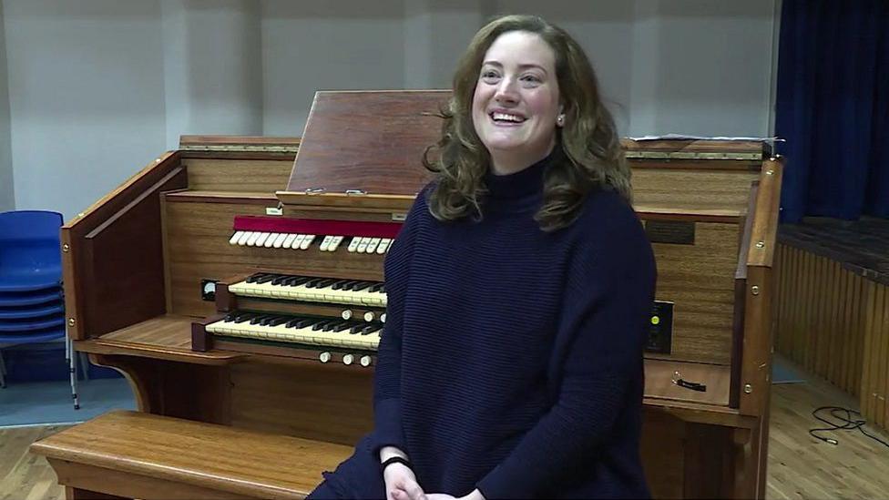 Alice Longbottom sat next to the large wooden pipe organ