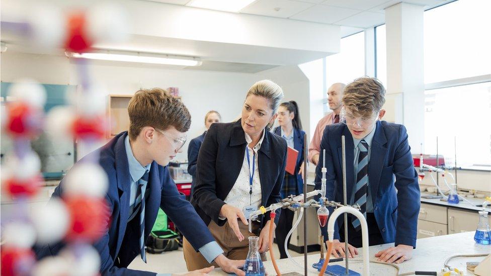 A teacher talks to pupils in a science lab