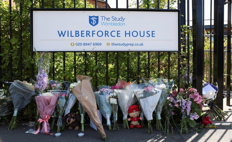 Floral tributes are laid outside a school gate