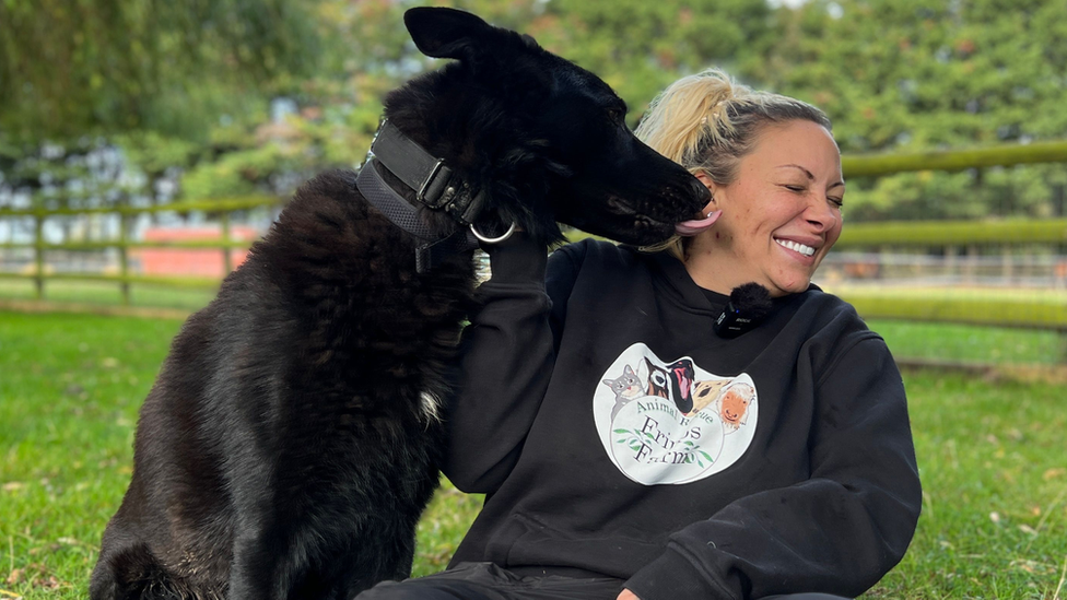 Jodie Marsh scrunches up her face and smiles as a black dog licks her ear