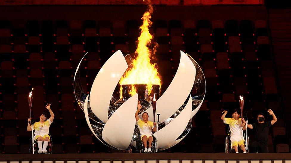 three-japanese-athletes-light-massive-olympic-flame-in-stadium