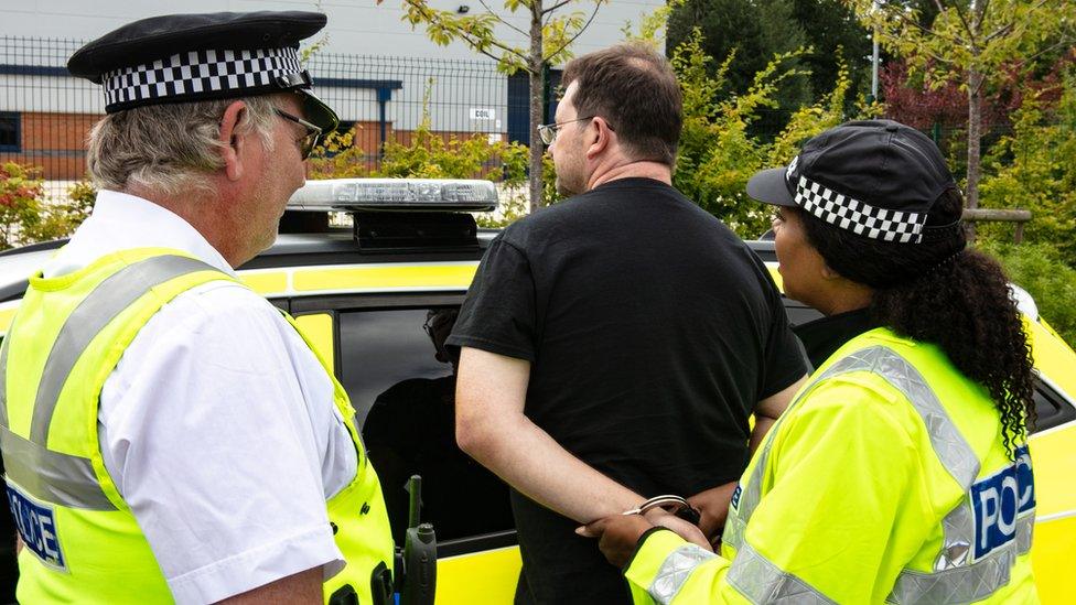 Police officers putting handcuffs on a man