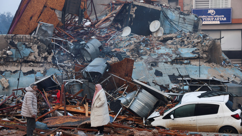 People look at rubble and damage following an earthquake in Hatay, Turkey