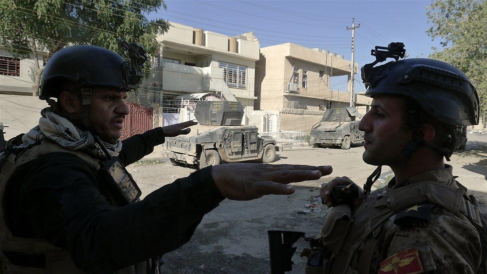 Abu Daoud, a sniper group leader, speaks to his commander in the Mualameen district of Mosul