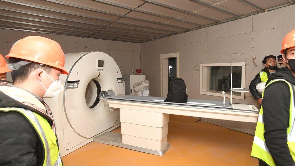 Workers set up a CT scanner inside the hospital