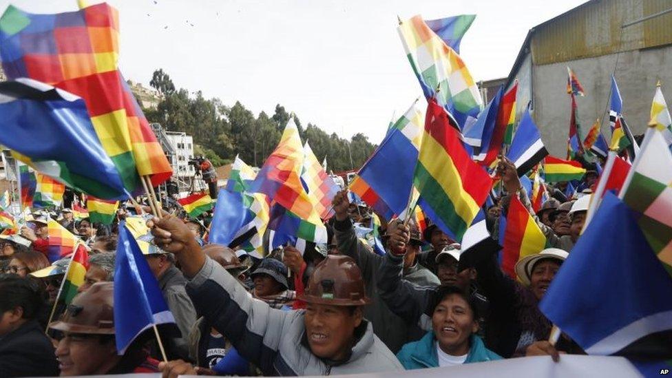 Supporters of President Evo Morales wave Wiphala and Bolivian flags during a ceremony where Morales signed documents for the expansion of the road that connects the capital with the nearby city of El Alto, in La Paz, on 22 February, 2016,