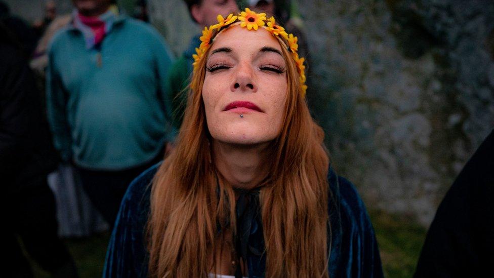 A woman stands silent inside the stone-circle during Summer Solstice at Stonehenge, where some people jumped over the fence to enter the site to watch the sun rise at dawn of the longest day in the UK.