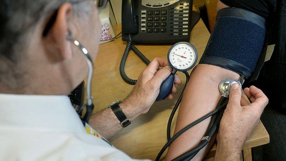 GP checking patient's blood pressure