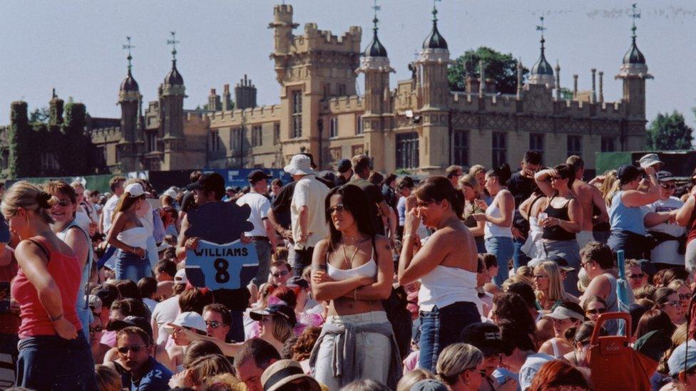 Crowd during the day at one of Robbie Williams' sold out shows at Knebworth Park with Knebworth House in the background.