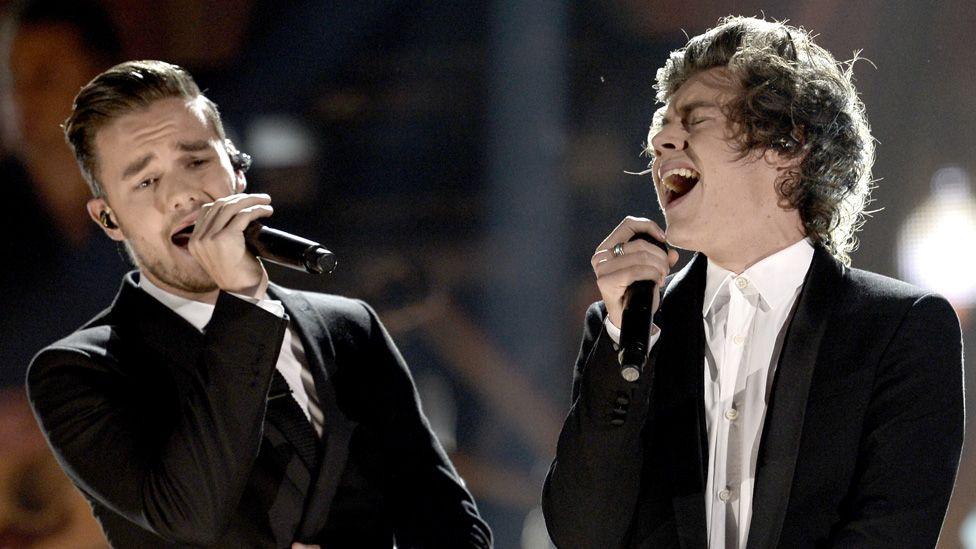 Liam Payne and Harry Styles together on stage in smart black jackets both singing