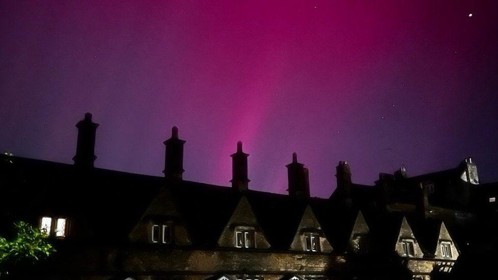 Long terrace of homes with line of chimneys with pink and purple sky above