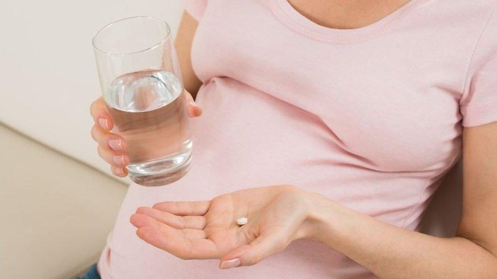 Pregnant woman taking a pill