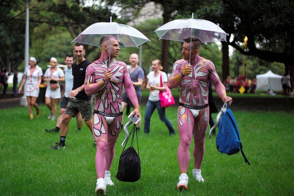 Two men in full pink bodypaint use umbrellas in the Sydney Gay and Lesbian Mardi Gras festival, arriving during early rain showers in Sydney, Australia March 4, 2017.