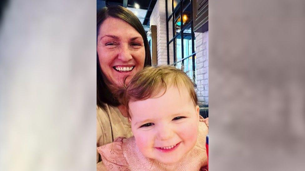 Gemma and Maya Chappell smiling at the camera. Gemma's straight brown hair reaches her shoulders and she wears a cream top. Maya has short blonde hair and wears a peach-coloured top. 