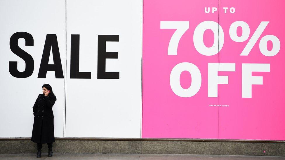 A woman standing in front of a sale sign.