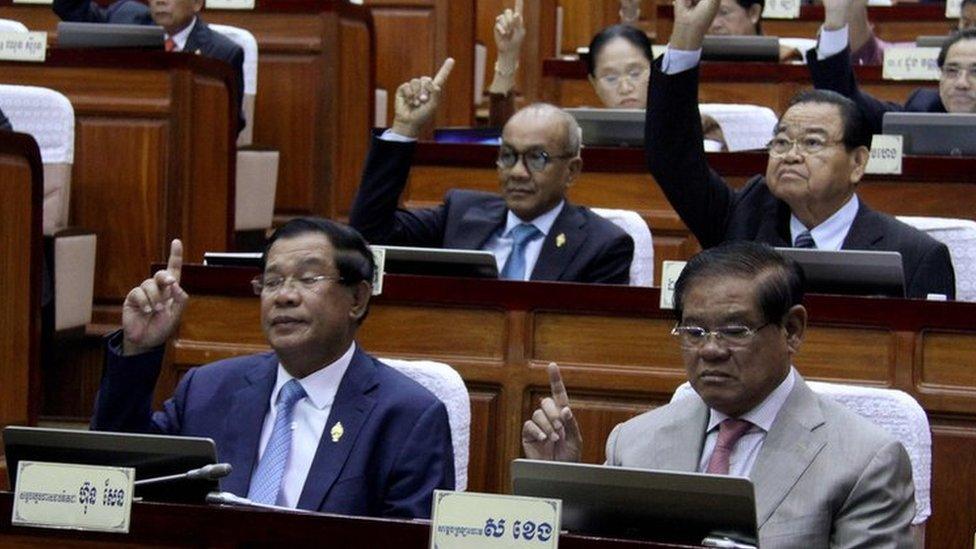 This handout taken and released on February 20, 2017 by the Cambodia National Assembly shows Cambodia"s Prime Minister Hun Sen (front L) and other lawmakers voting during the parliament meeting at the National Assembly building in Phnom Penh. They have their right hands raise in the air.