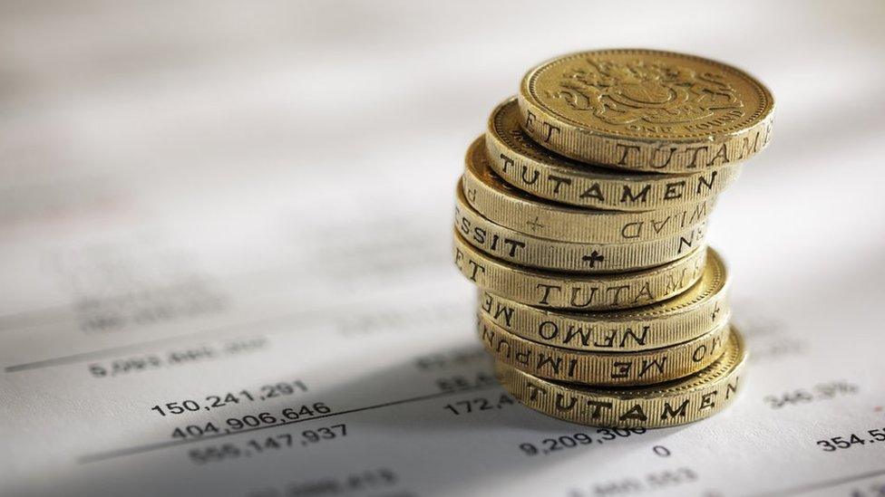 Pile of pounds coins on top of financial data