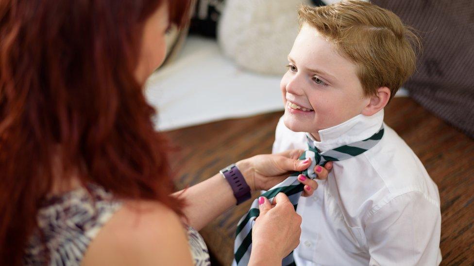 School pupil having his tie tied.