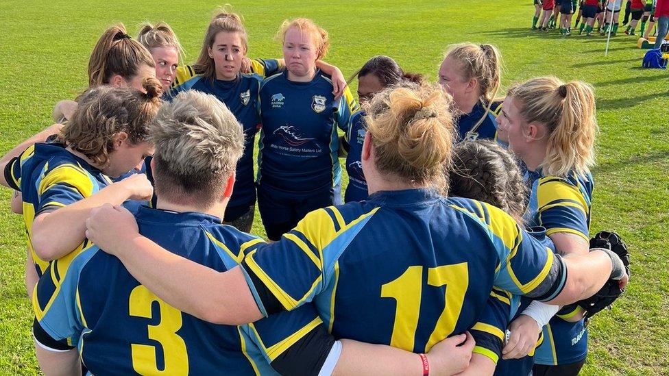 A women's rugby team huddling togehter