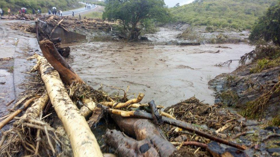 People gather around the road that was destroyed by heavy rain near Kapenguria, West Pokot County