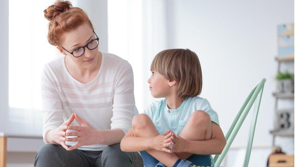 A female professional having a serious conversation with a young boy