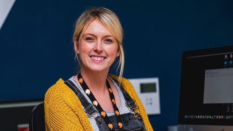 Dynes yn gwisgo lanyard efo'r bathodyn oren