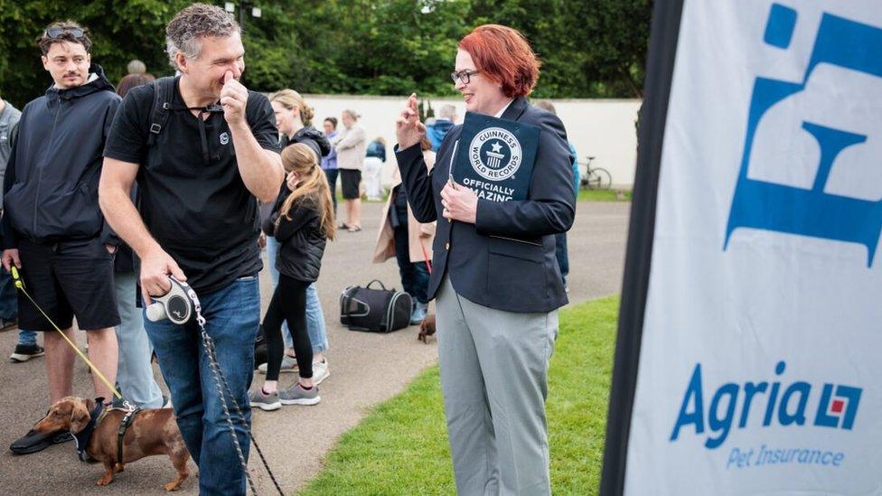 A Guinness World Records official crosses her fingers in response to an owner's question