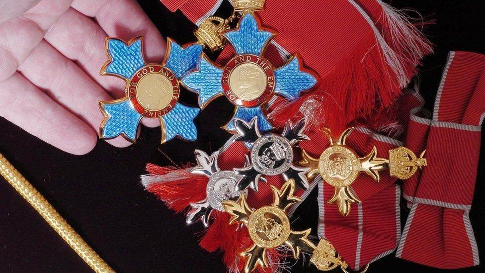 A number of different medals on a red and black uniform 