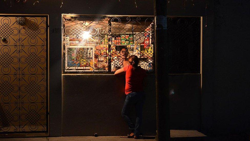 A woman buys at a store at the Reparto Lempira neighborhood in San Pedro Sula, 240 km north of Tegucigalpa, Honduras on March 23, 2016. Families are moving out of a neighborhood in San Pedro Sula after they were threatened by "Mara 18" gang members, who gave them 24 hours to do so.