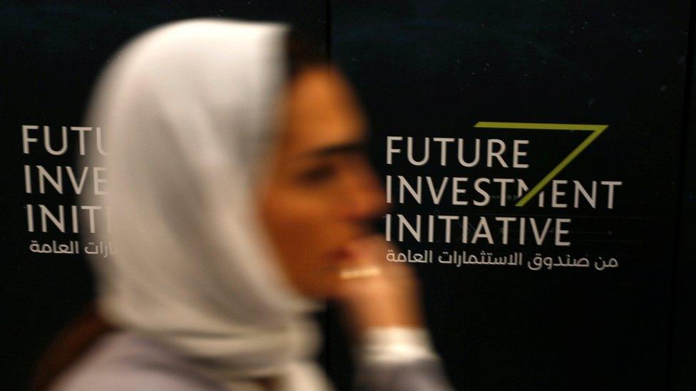 A woman walks past a sign during the Future Investment Initiative conference in Riyadh, Saudi Arabia (24 October 2017)