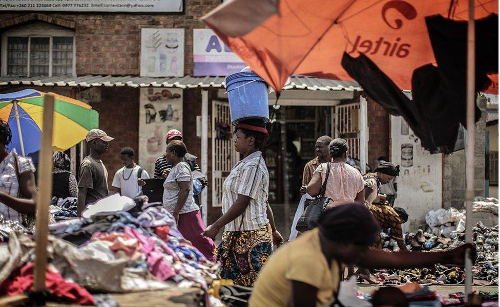 People shop at an open air market on Patrice Lumumba road in Lusaka on November 12, 2014, a day after the burial of the late Zambian president