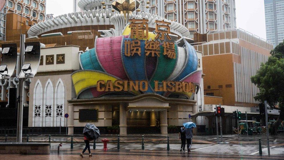 Pedestrians walk past Casino Lisboa in Macau which has closed because of Typhoon Mangkhut on 16 September 2018