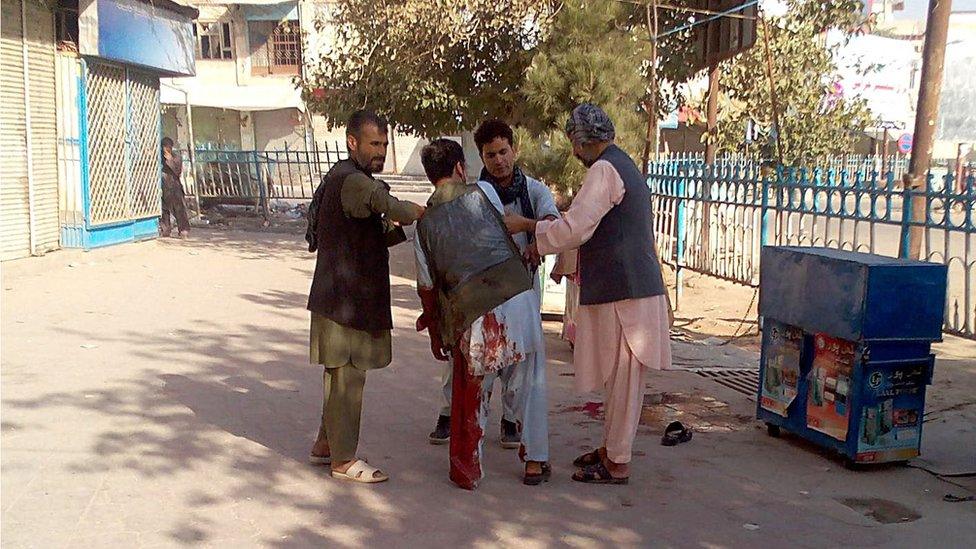 Afghan men assist a wounded civilian in a street of Kunduz city, north of Kabul, Afghanistan, Thursday, Oct. 1, 2015