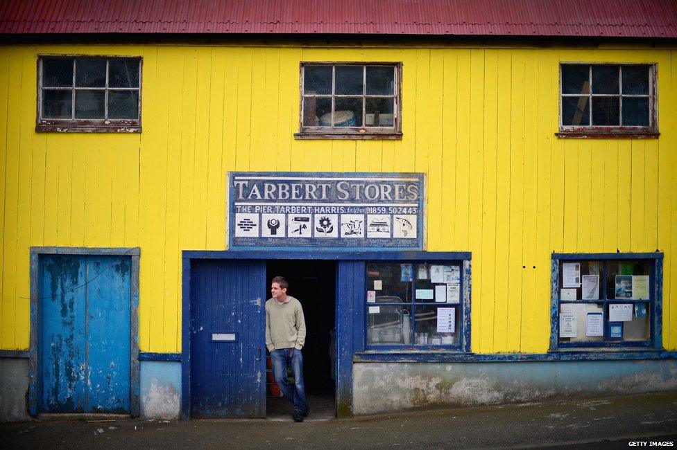 A shop worker stands in the doorway of the Tarbert Stores in Harris, Scotland