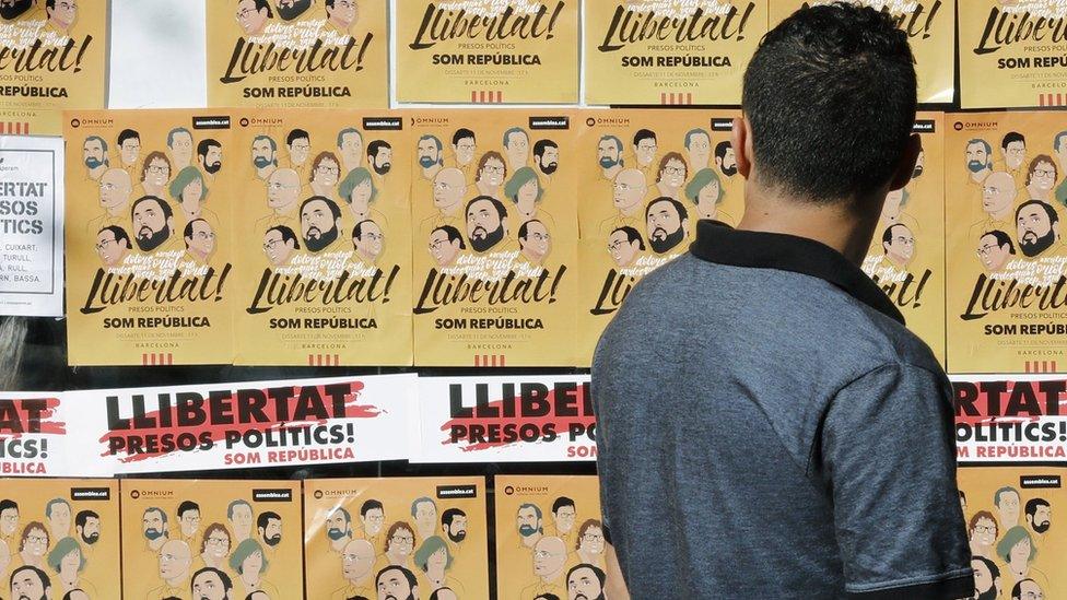 A man looks at posters during a demonstration to protest against the imprisonment of eight former members of Catalan government