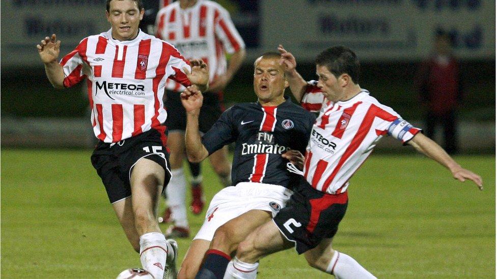 A Derry City player tackles a PSG player during a game in 2006