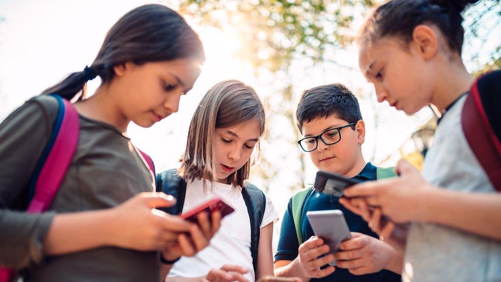 Four children looking at their phones