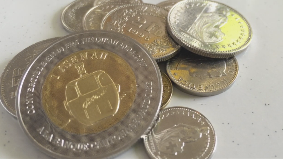 A close-up of an Isenau coin among Swiss francs