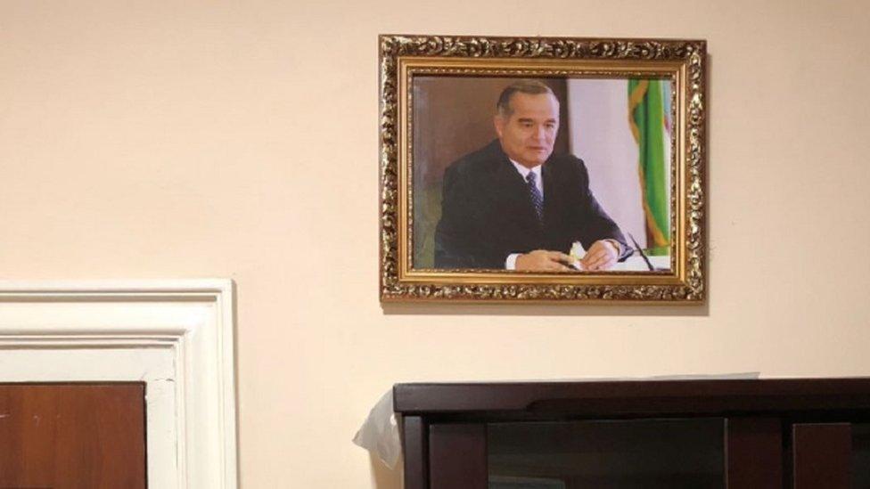 A photo of former Uzbek President Islam Karimov hangs on a off-white wall in a Uzbek hospital