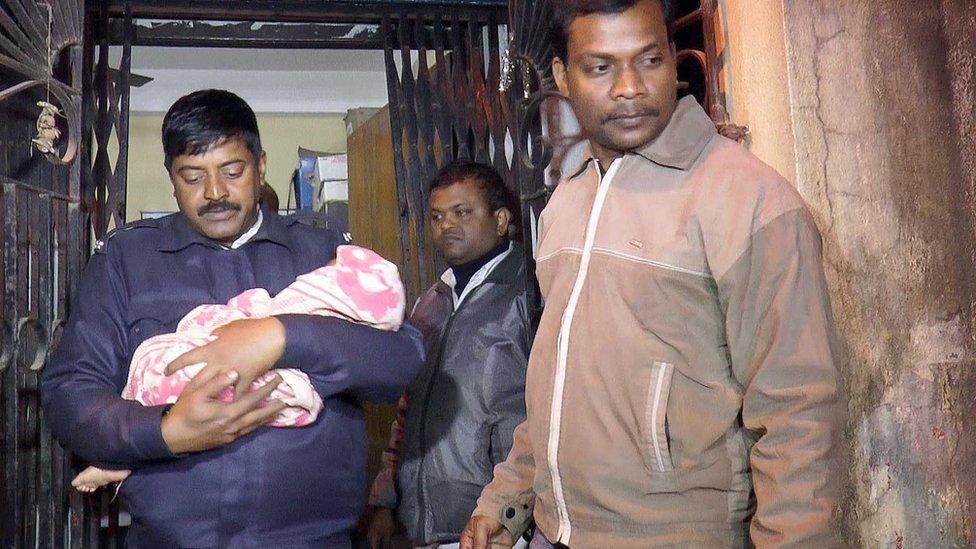 A police officer takes a baby girl from the room in Kolkata