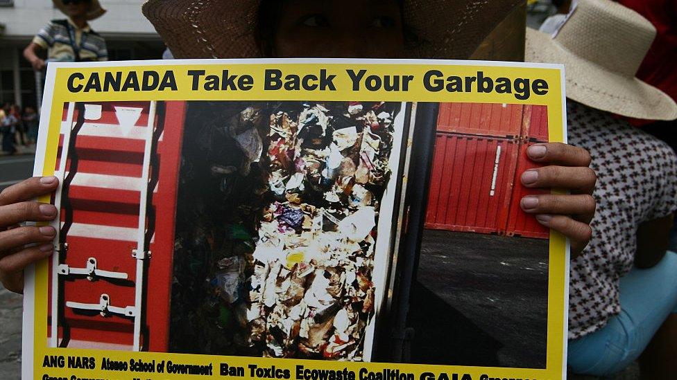 A protesters holding a poster of the shipping container in the port of Manila.